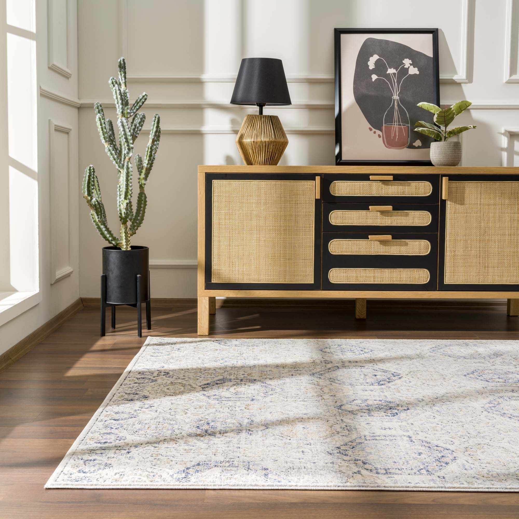 Parkerfield Area Rug placed in a sunlit room with wood furniture and plants. Navy and beige hues blend with modern and coastal decor.