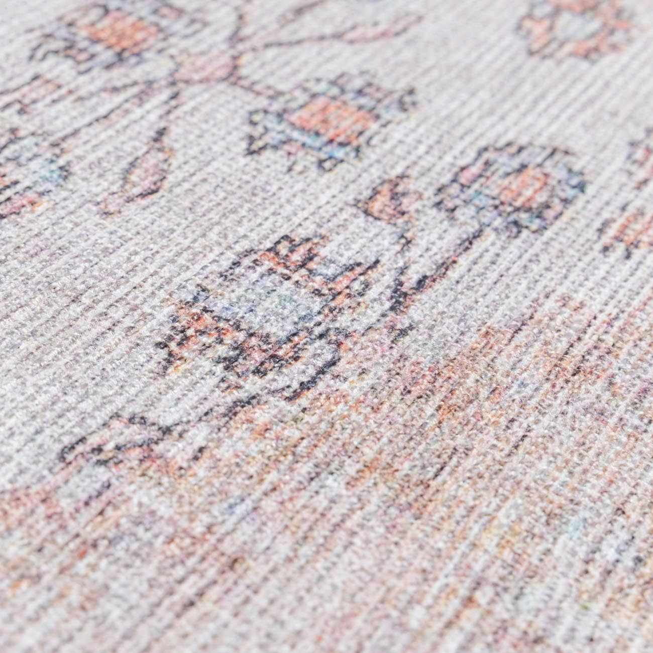 "Macro view of the Moora washable area rug's floral pattern, highlighting its fine weave and soft vintage color palette."