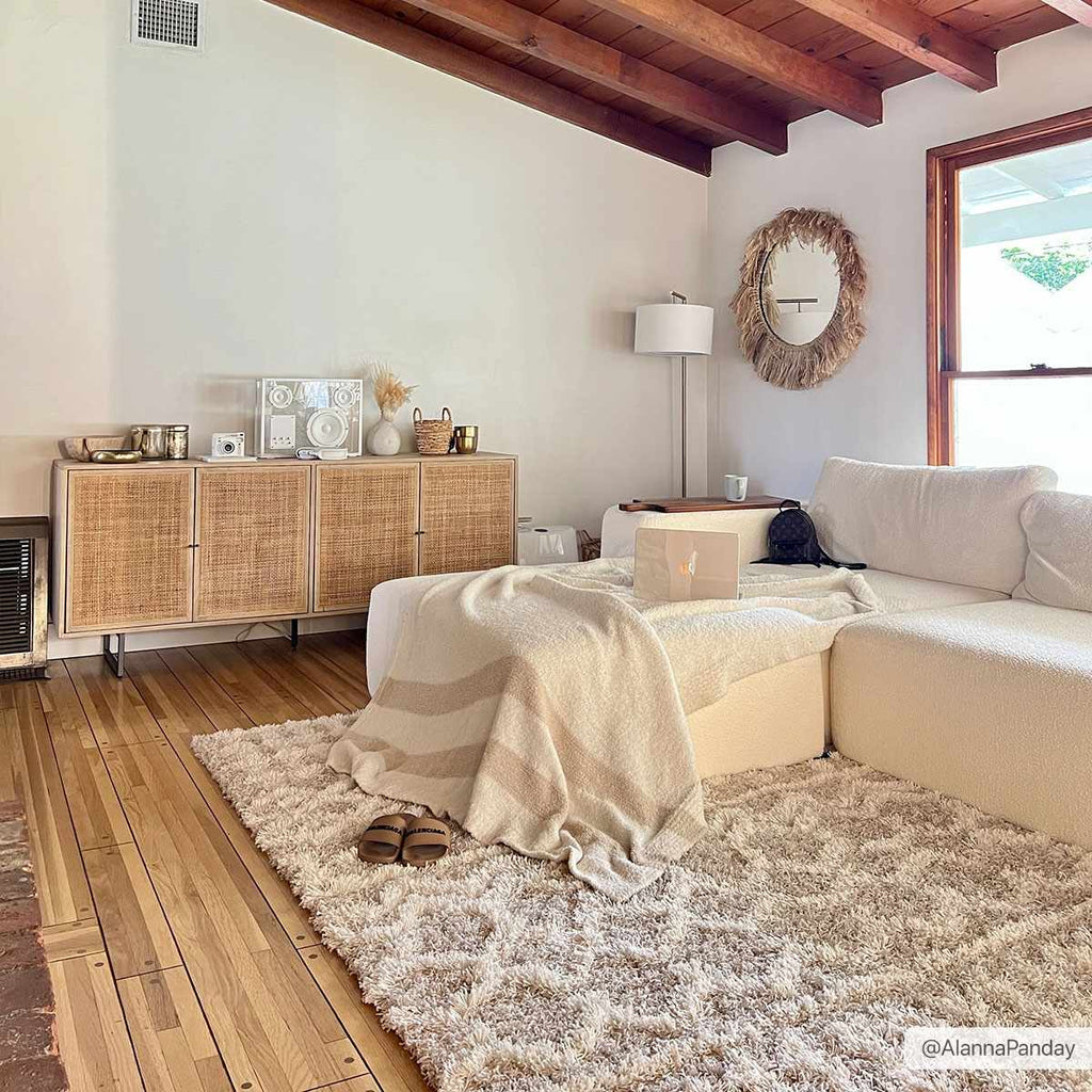 "Prompton Cream Plush Area Rug in cozy living room with white sectional and wood accents, ideal carpet for home decor in Bohemian style."