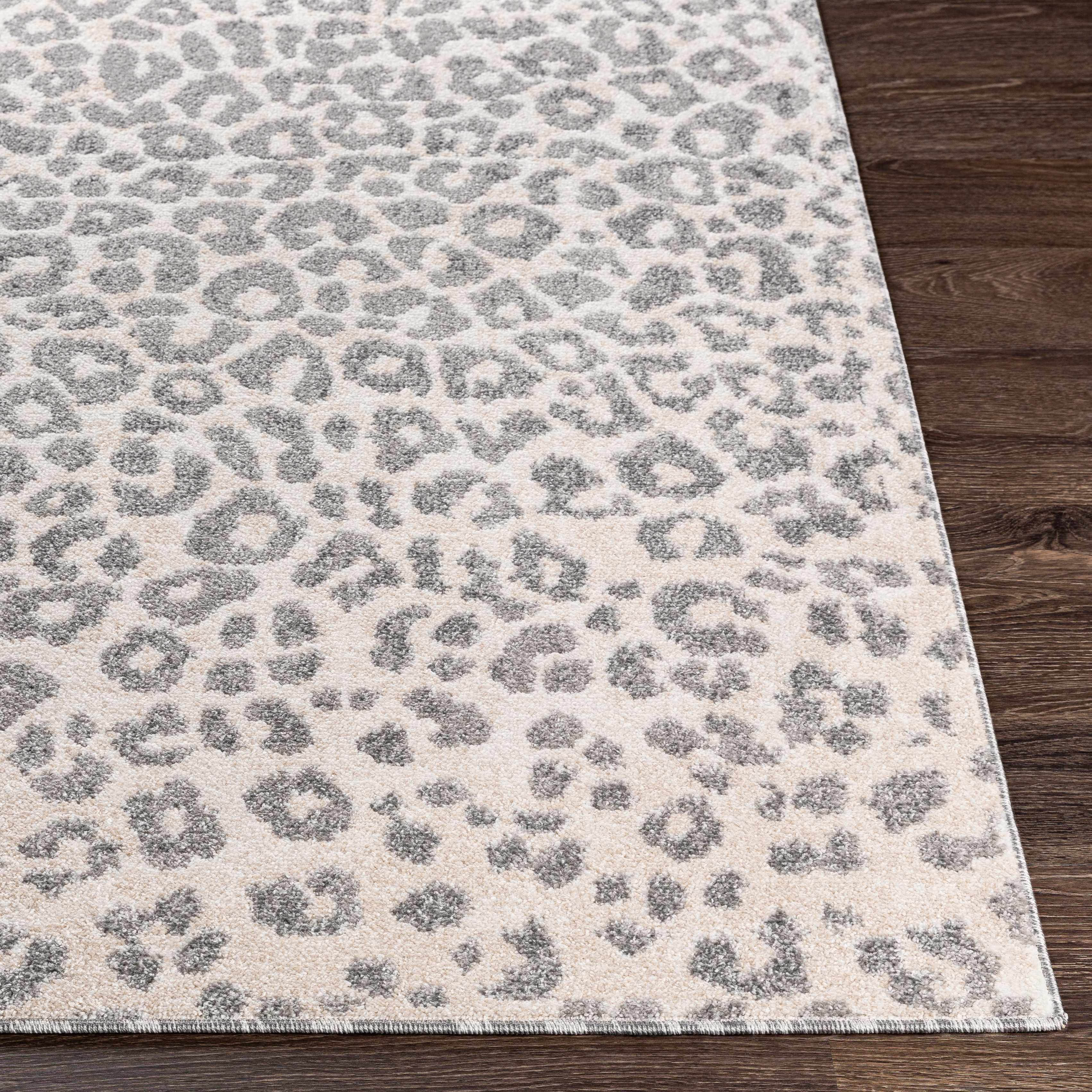 "Detailed corner of the Liversedge Leopard Print Rug on hardwood floor, highlighting its medium pile and stylish neutral tones."